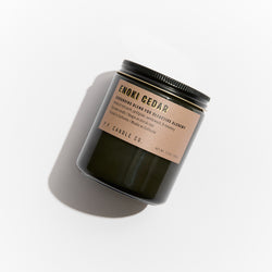 P.F. Candle Co. Wholesale - Enoki Cedar 7.2 oz Alchemy Scented Soy Wax Candle - Product - Alchemy Candles feature smoke-colored glass vessels, black metal lids, and gold-leafed labels inspired by vintage window lettering.