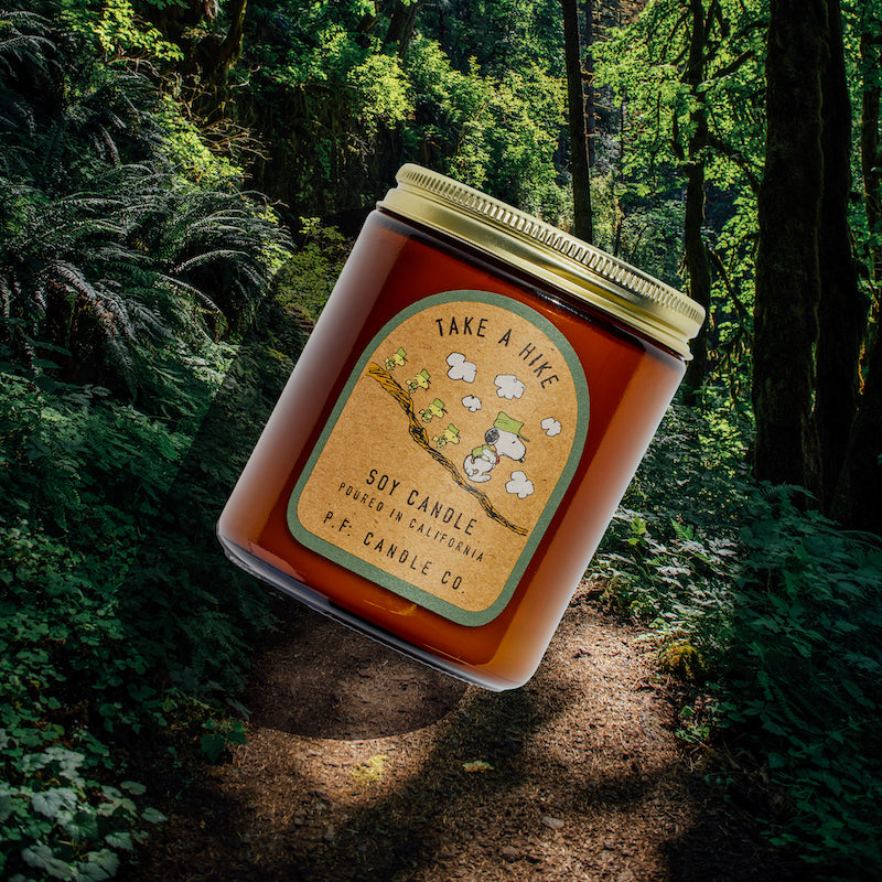 P.F. Candle Co. Wholesale Take a Hike for Peanuts Standard Candle - Lifestyle - Inspired by inquisitive strolls along sun-soaked trails and bonding with buddies amongst towering trees, Take A Hike features aromatic, fresh notes of juniper shrub, pine cones, and tree sap to encourage moments of tranquility in any space.